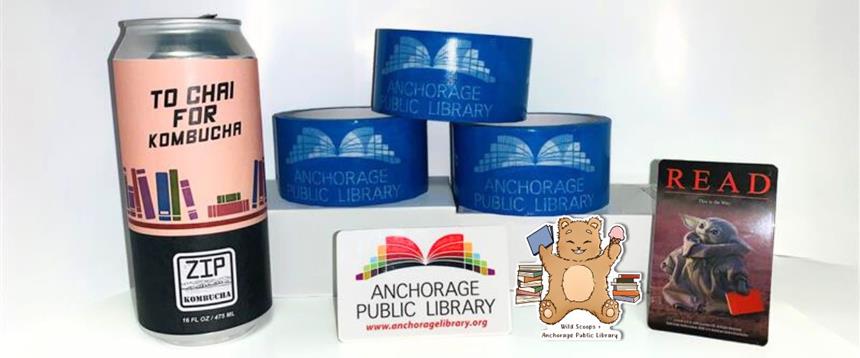 Can of To Chai for Kombucha from Zip Kombucha, rolls of duct tape with the Anchorage Public Library logo, the logo and Baby Yoda library cards and a sticker with a bear holding a book and ice cream cone